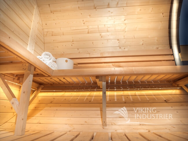 Interior bench seating with lighting inside the Viking Industrier Delight Outdoor Sauna 2.4 x 4.3m on a wooden background.