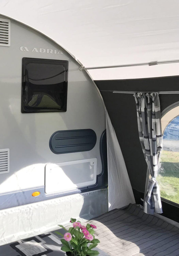 Corner interior of the Walker awning attached to the Adria caravan, featuring curtained window and grey floor mat.