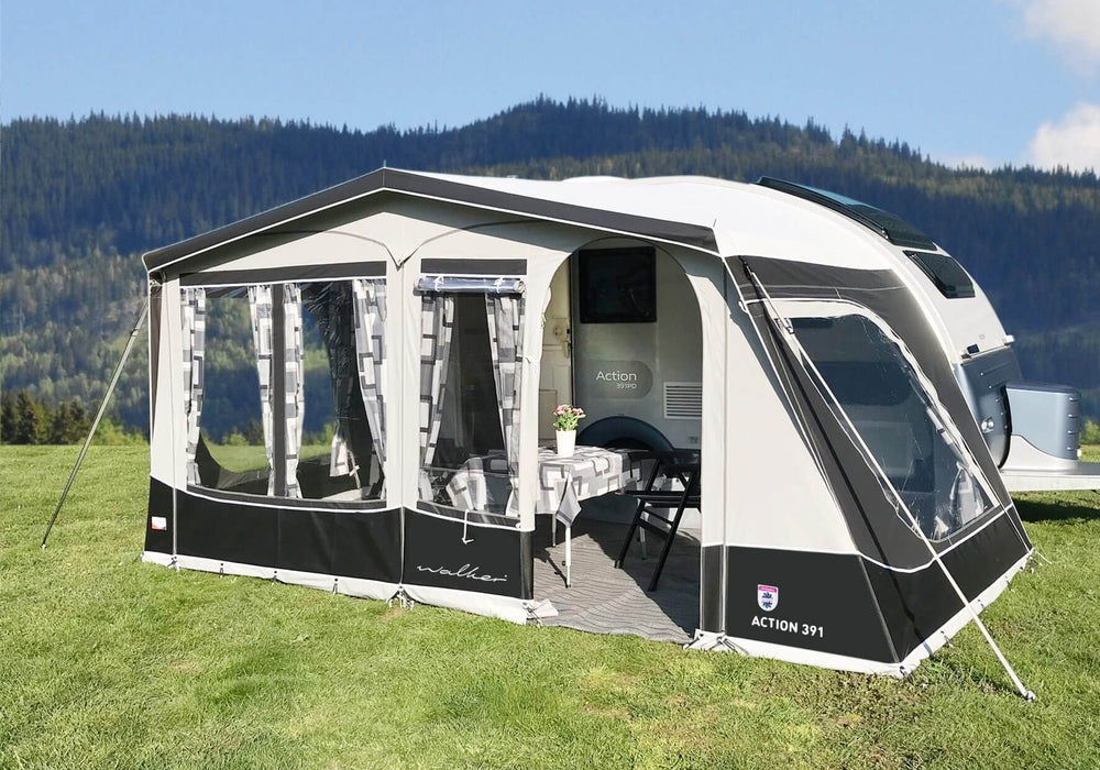 Angled front view of the fully enclosed Walker awning fitted to the Adria Action 391 caravan, set against a forested mountain.