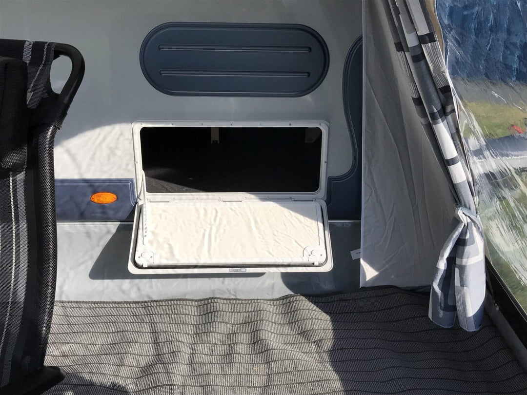 Interior view of the Walker awning showing the side access panel of the Adria Action 391 caravan, with chair beside it.