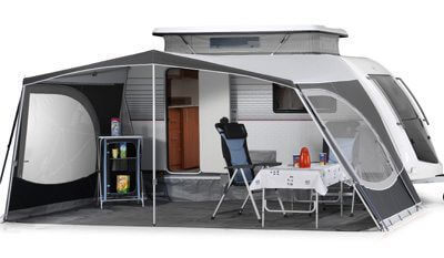 Walker Kip Kompakt half-enclosed awning showing additional storage shelf, two chairs, and a table with red kettle setup, on white background.