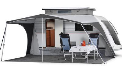Walker Kip Kompakt canopy-style awning setup with two chairs and a table placed on the groundsheet outside the caravan, with white background.