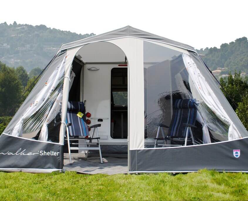 Front-facing view of Walker Kip Shelter Awning with two chairs, curtains, and open entrance setup on grass.