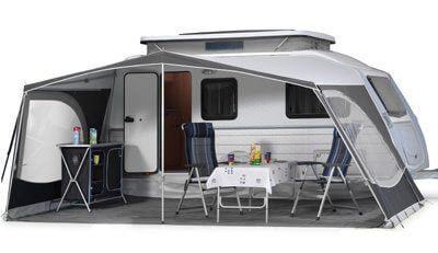 Walker Kip Vision awning with side shelving unit and camping furniture, showcasing semi-enclosed configuration on a Kip Vision caravan, on white background.