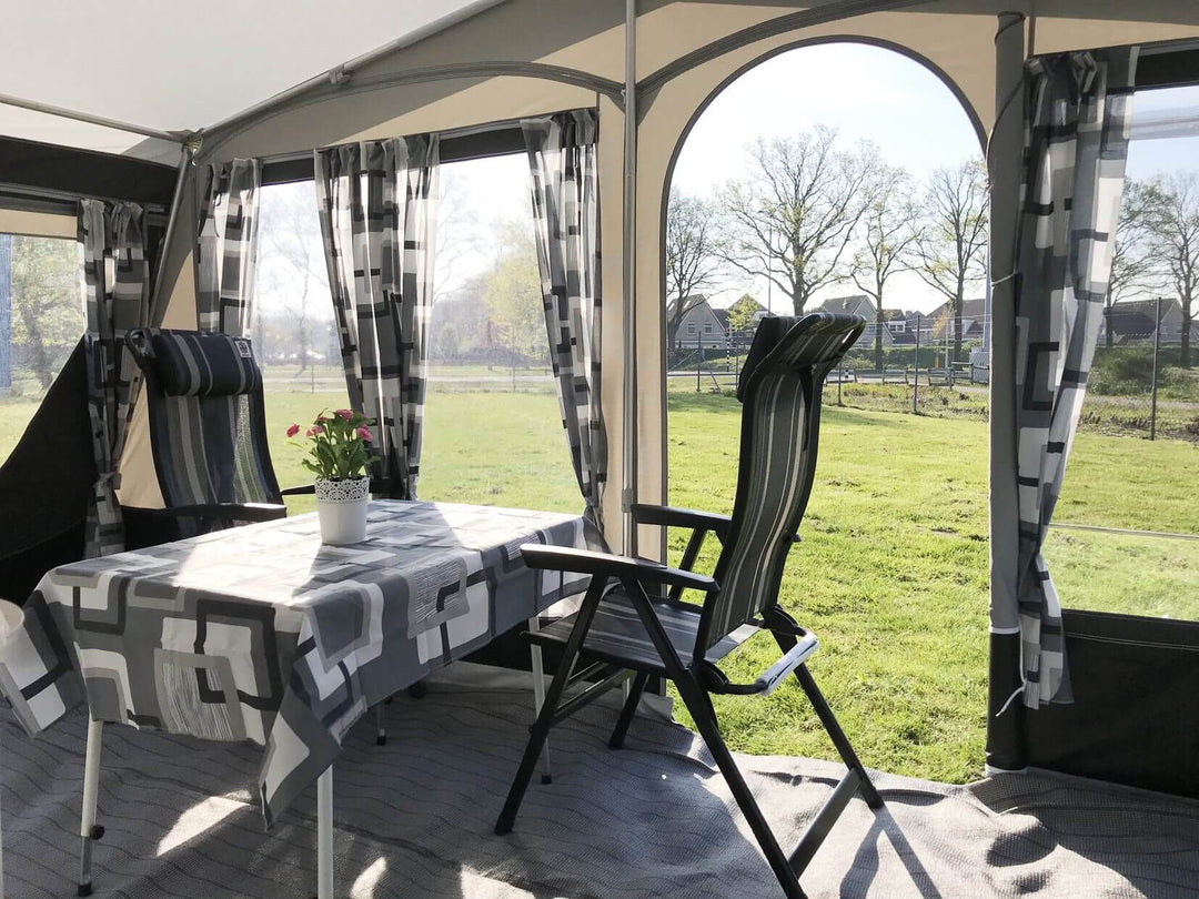 Inside look at the Walker awning living space with table, chairs, and floral centerpiece, overlooking a grassy landscape.