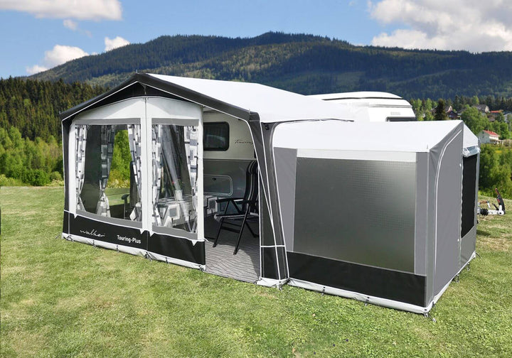 Walker Touring-Plus awning fully assembled on a Trigano Silver caravan with optional rear storage annex, set up on a grassy site with mountains in the background.