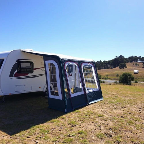 A small air awning on bumpy ground next to a caravan