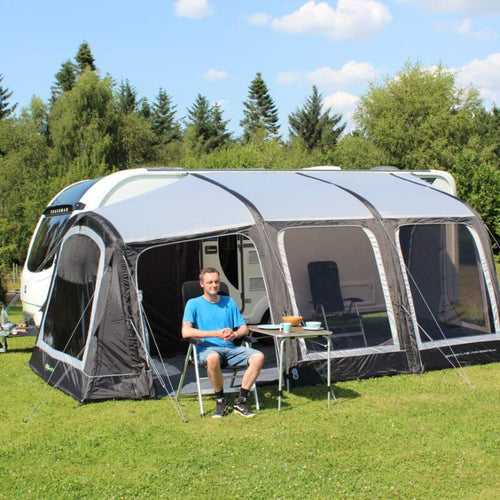 A man sat on a chair outside an Outdoor Revolution awning in a field