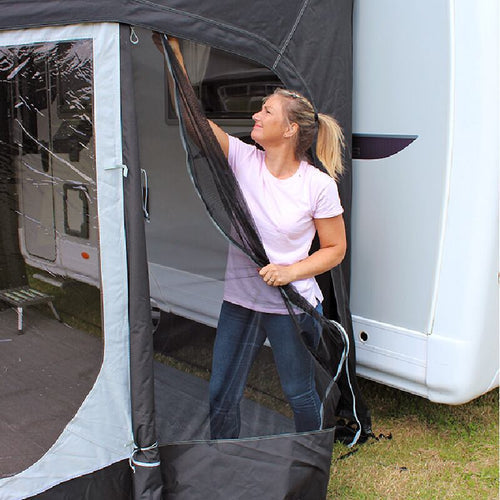A woman taking down the side door from a caravan awning