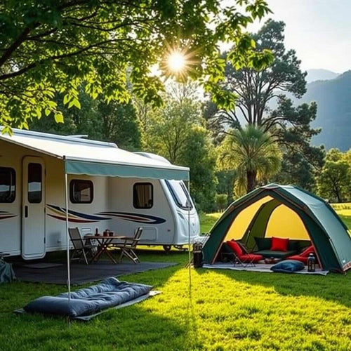 An awning next to a tent, in front of a caravan in field in front of trees