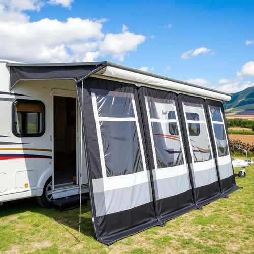 A black and grey air awning next to a white caravan in a field with blue sky and clouds above