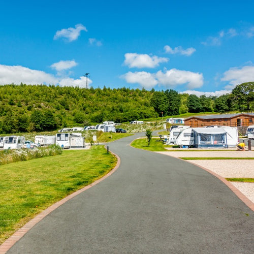 A road leading to a caravan park with several caravans and awnings