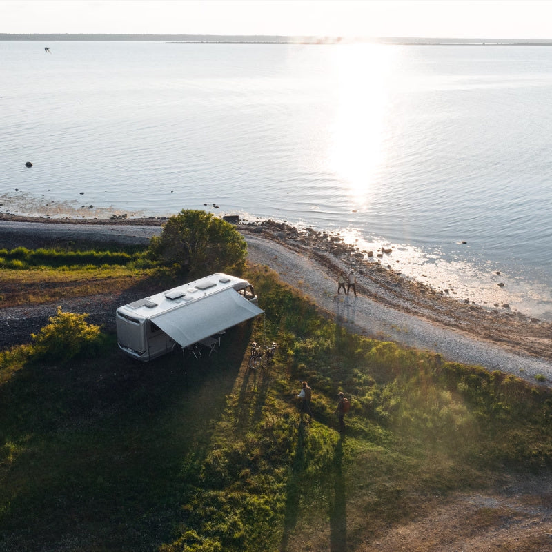 Aerial image of an RV with an awning next to a large lake