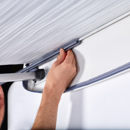 A close up showing hands adjusting a caravan awning rail