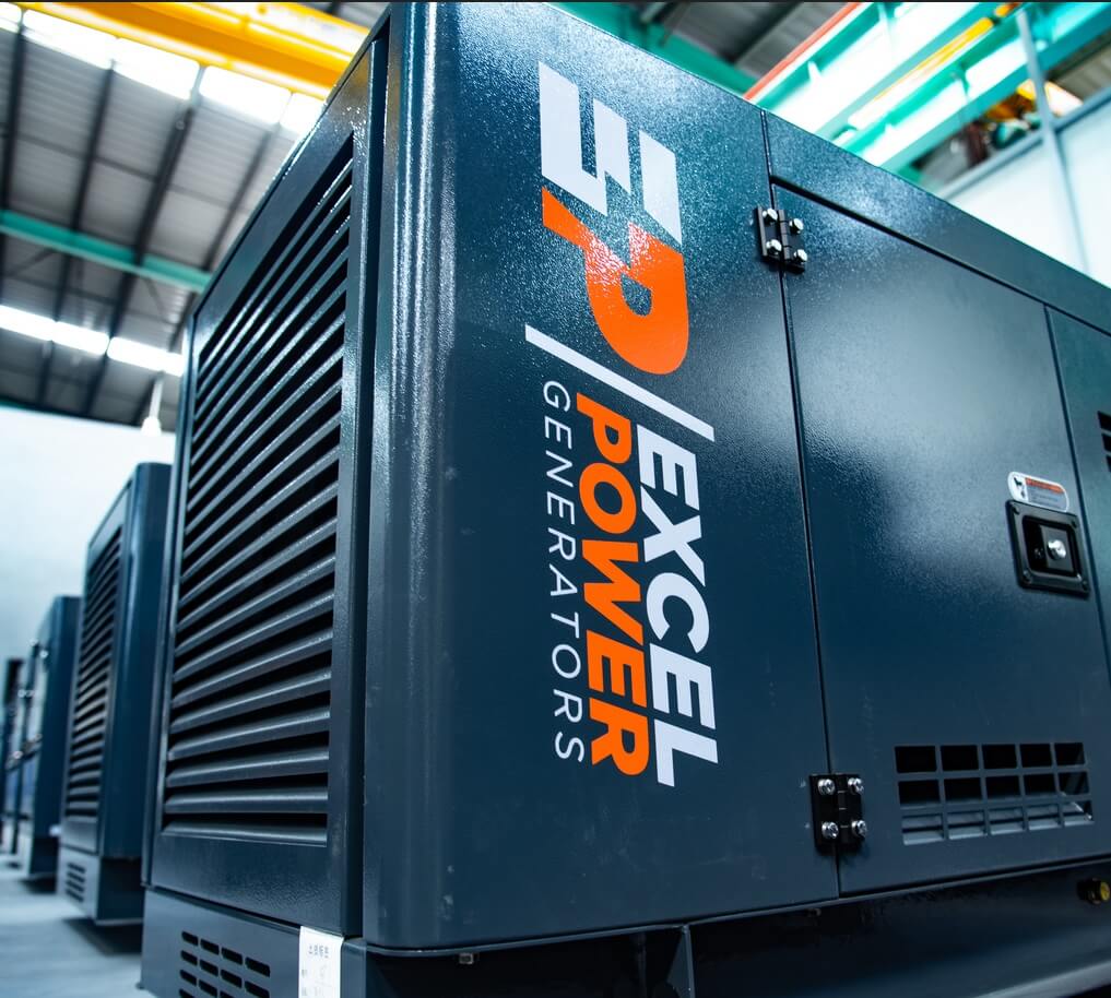 Close-up of Excel Power XL-DK-11S generator showing Excel Power Generators logo and vent grill in a warehouse setting.