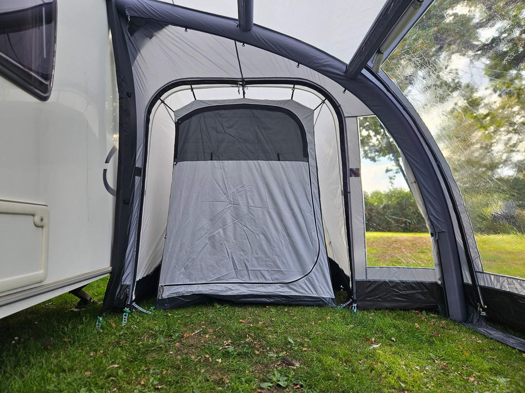 Interior view of the Sunncamp Ultima Versara Air 390 Deluxe Porch Awning showing the inner sleeping annex tent with grass floor and trees visible outside.