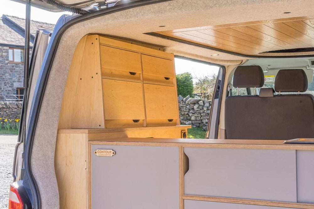 The Campervan Bereau Sideboard is installed along the rear side of the van, featuring multiple wooden drawer compartments and a clean plywood finish, viewed through the open back doors.