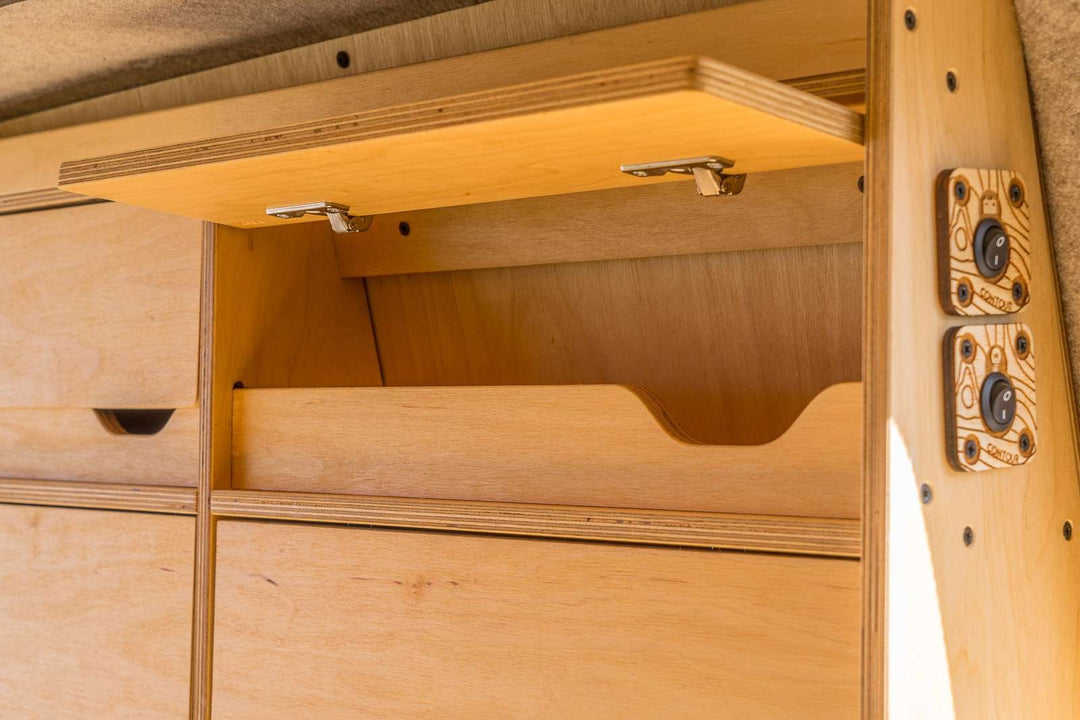 A detailed view of the Campervan Bereau Sideboard reveals the lift-up cabinet door mechanism and internal shelving, designed for secure and accessible campervan storage.