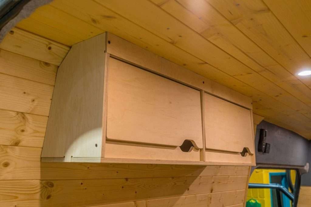 Wide interior view of the Campervan Cornice Top Cabinets installed along the campervan wall with warm wooden ceiling and lighting.