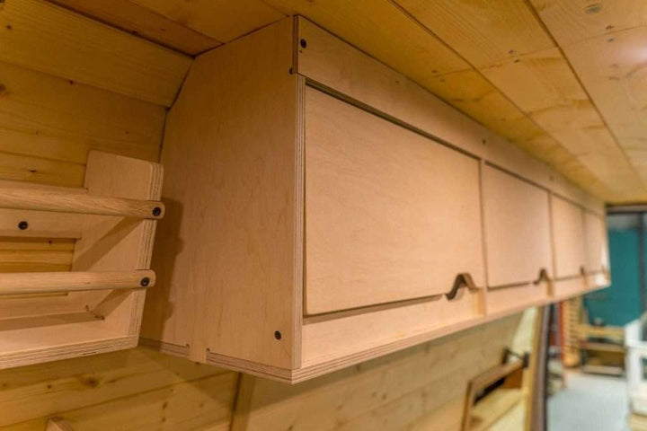 Side perspective view of the Campervan Cornice Top Cabinets installed above the campervan window along the wooden wall.