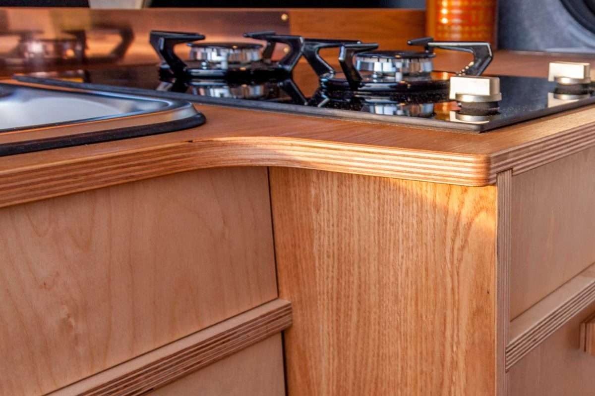 Corner countertop detail of the Campervan Foss Kitchen Unit featuring the built-in sink, gas hob, and curved wooden worktop finish.