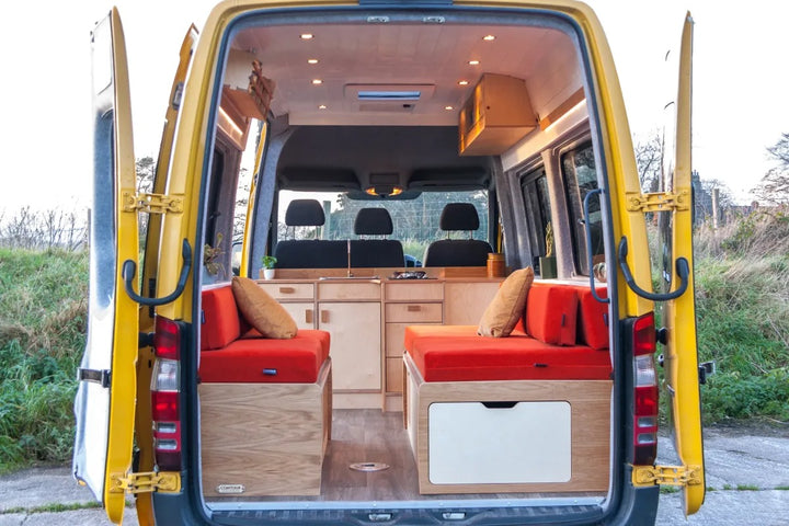 Rear interior view of the campervan highlighting the Campervan Foss Kitchen Unit and seating layout with bright yellow van exterior doors open