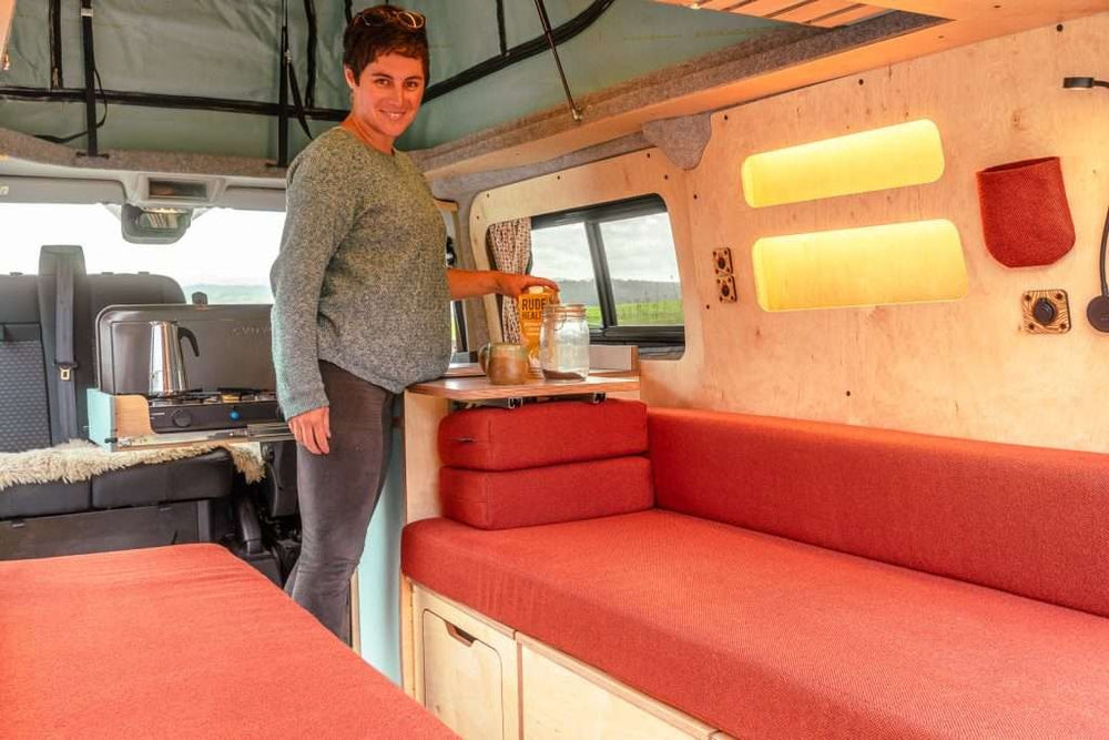 Interior lifestyle view of the Campervan Helm Kitchen Unit installed in a campervan with seating, storage, and warm ambient lighting.