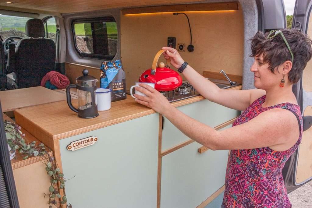 Campervan Ranger Kitchen Unit woman pouring tea beside the kitchen counter with integrated hob and sink.