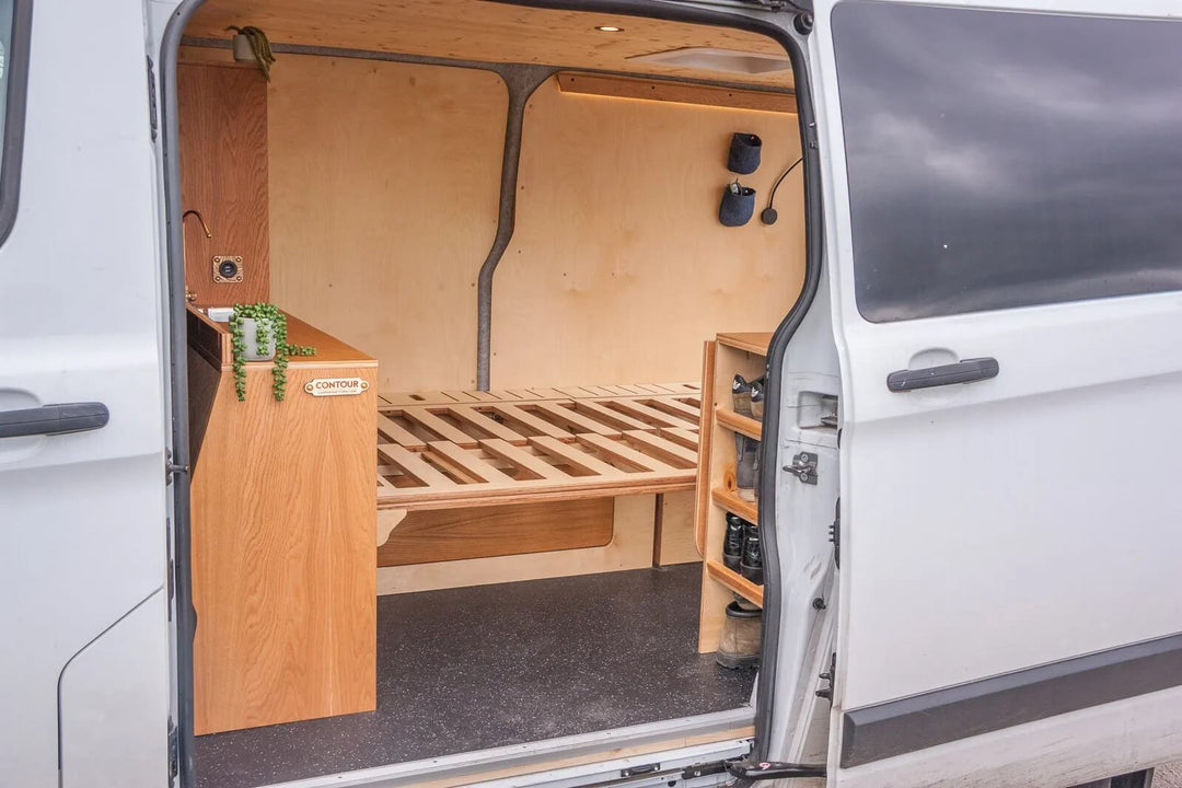 The Campervan Rig Sideboard is shown from the rear doors, revealing open shelving, cupboard storage, and the extended bed frame system designed for efficient space use.