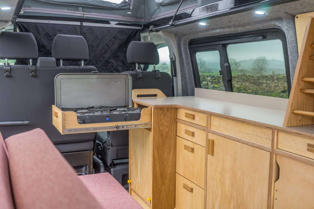 Campervan Squall Kitchen Unit conversion layout with fridge, hob and cabinetry inside campervan, scenic countryside setting.