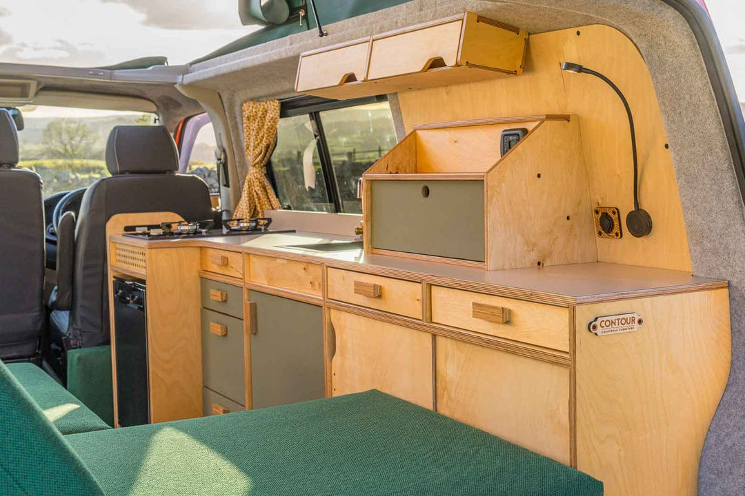 Campervan Squall Kitchen Unit complete rear setup with green bench cushions and full kitchen cabinetry, parked in countryside.