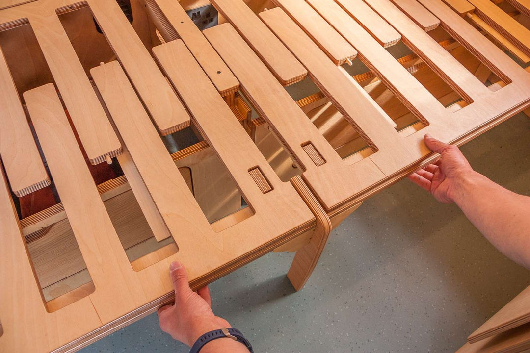 Campervan “Topo” Sofa-Bed close-up of removable wooden bed slats being positioned by hand inside a campervan interior.