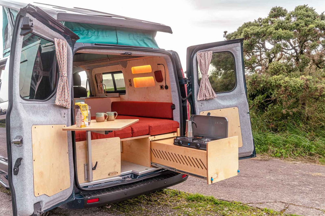 Campervan “Zawn” U-Berth Bench and Bed Unit interior view showing U-shaped bench seating converted into bed with overhead LED strip lighting inside van.