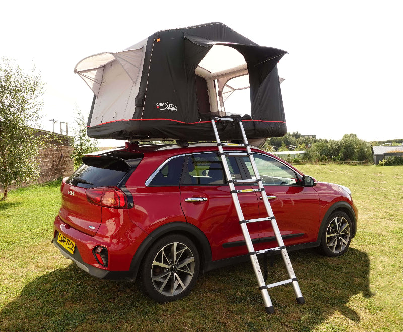 Camptech Queensland rooftop tent fully set up on a red vehicle, with an access ladder extended on grassy camping ground.