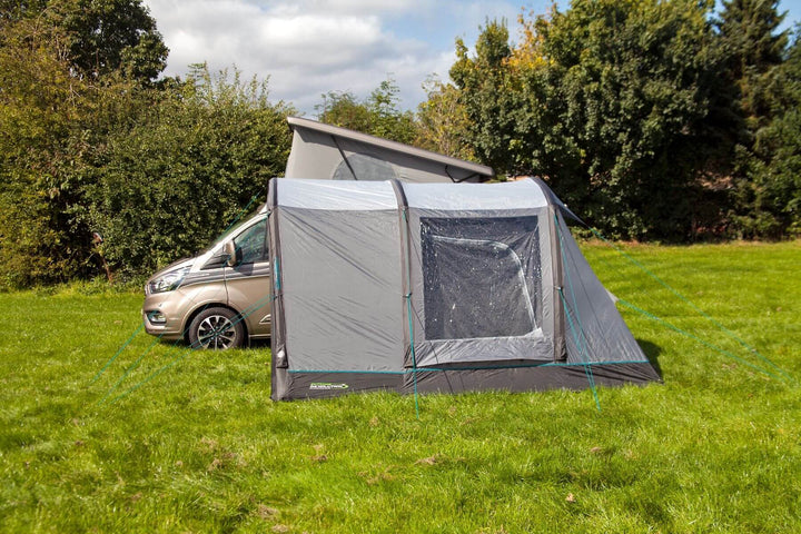Lifestyle view of the Outdoor Revolution Cayman Air T3 Lite driveaway awning attached to a campervan with a person relaxing under the awning on a grassy campsite.