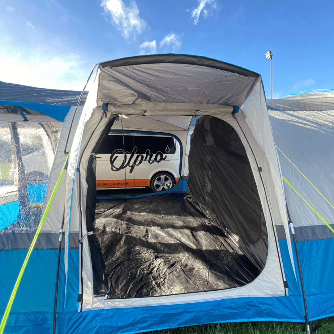 Interior view of the OLPRO Cocoon V2 campervan awning with the OLPRO van visible outside, set up on grass.