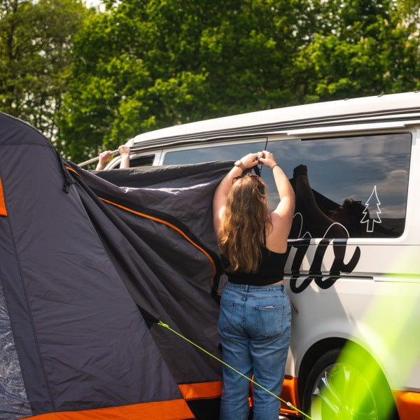 A woman connecting a Cubo Breeze V2 to the side of a campervan