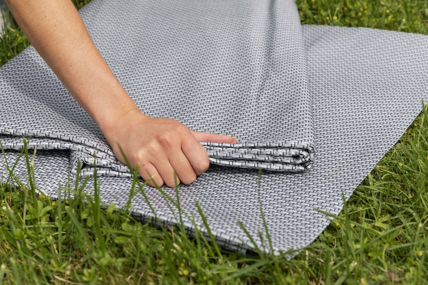 Hand folding Dorema Starlon awning carpet on a grass.