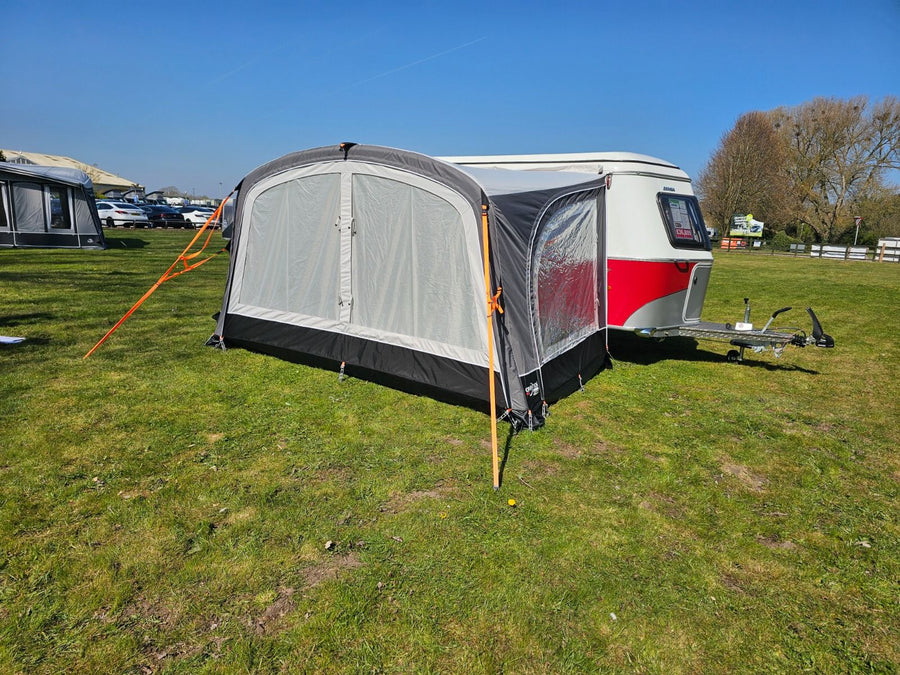 Camptech Majestic Eriba Caravan Awning attached to a red and white Eriba caravan on a sunny day, pitched on a grassy campsite with a clear blue sky in the background.