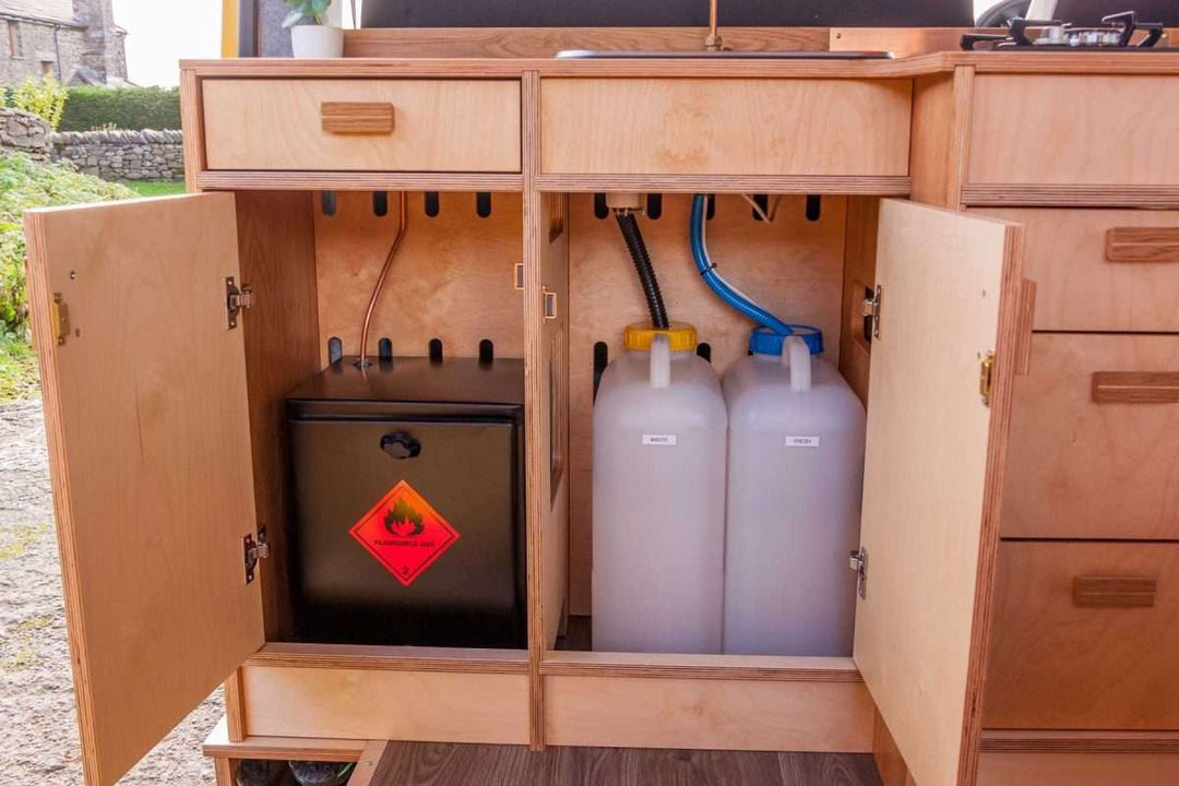 Under-sink cabinet view of the Campervan Foss Kitchen Unit displaying the water containers and gas storage compartment.