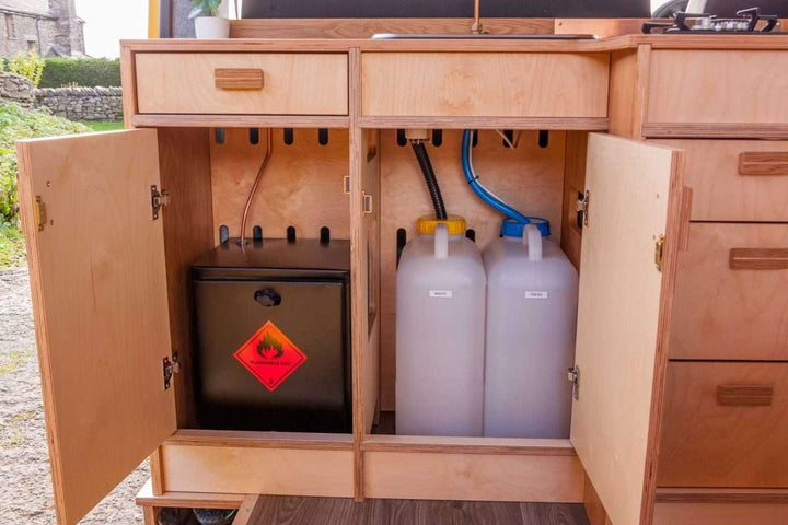 Under-sink cabinet view of the Campervan Foss Kitchen Unit displaying the water containers and gas storage compartment.