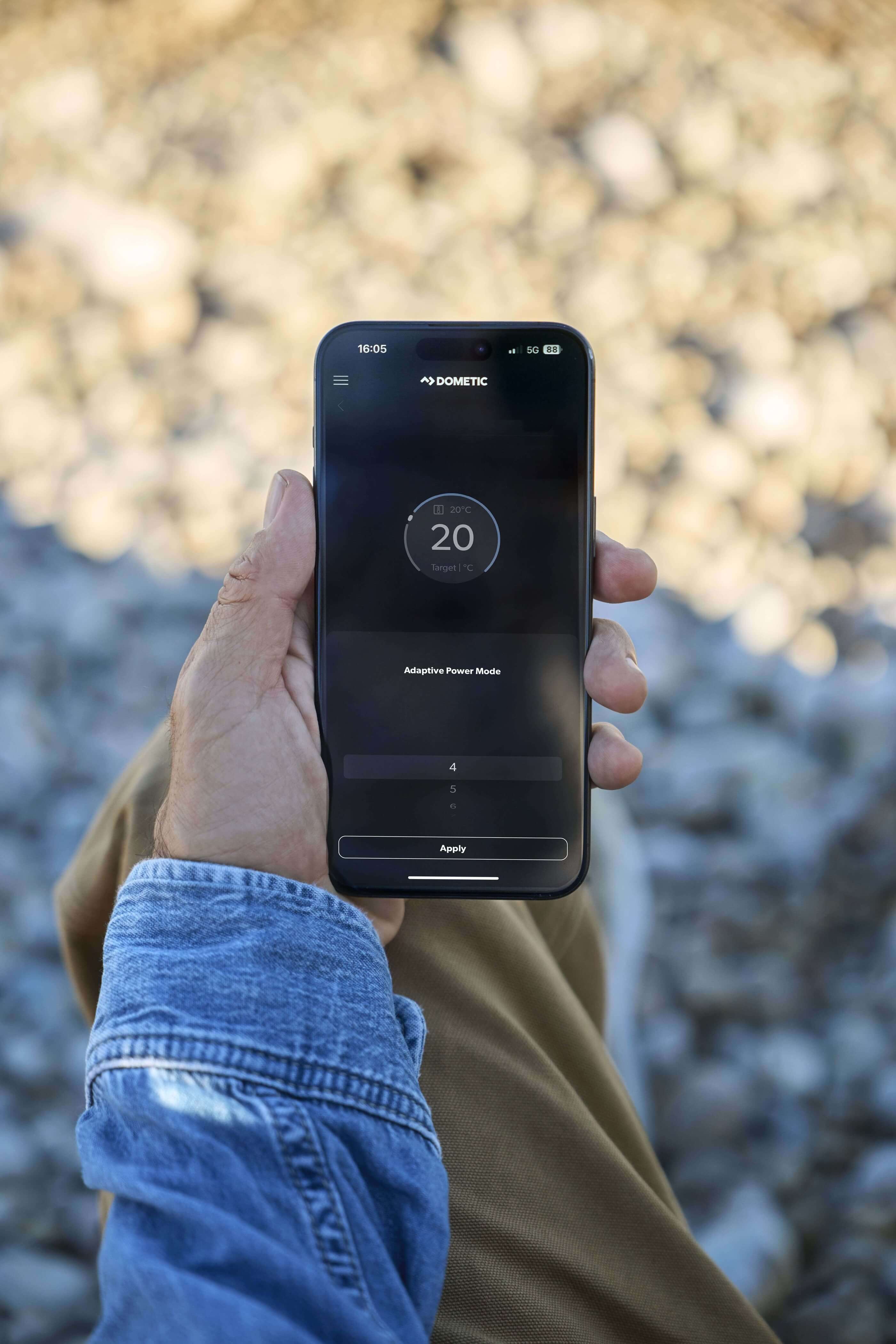 Person holding smartphone with Dometic app controlling FJZ7 2200 cooling settings.