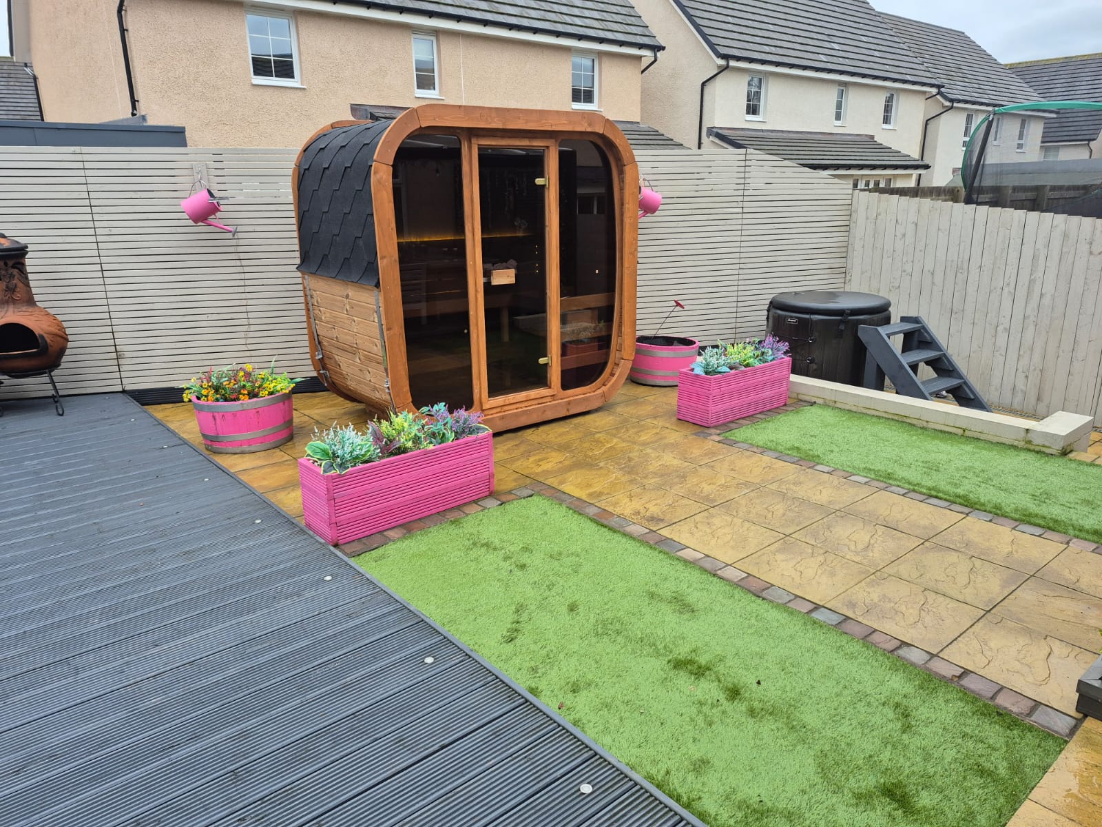 Wooden Icon 125 sauna pod with pink planters on a patio area
