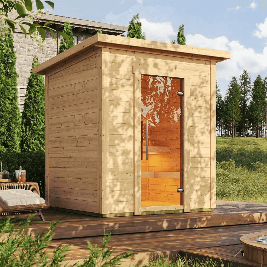 InMedias Brico Log Sauna installed on a wooden deck in a garden setting.