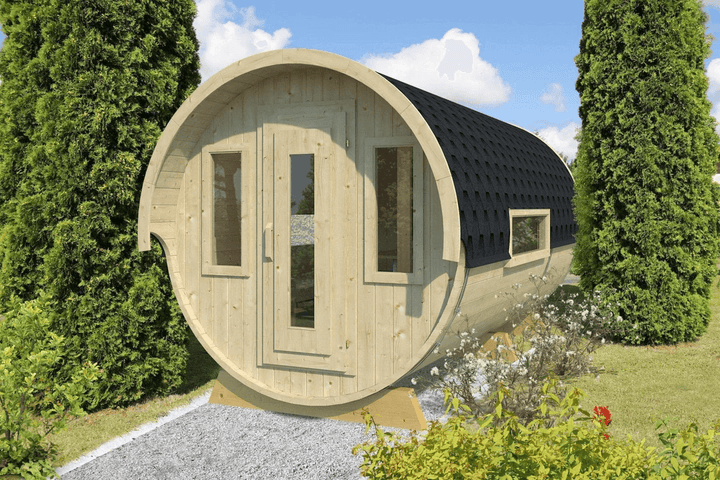 Photorealistic image of the InMedias Camping Barrel Royal 446 placed outdoors among green bushes and trees, with a gravel pathway and blue sky in the background.
