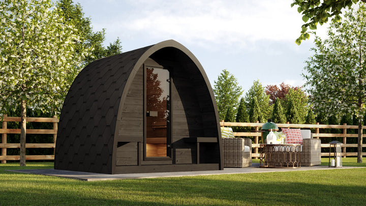 InMedias Sauna Pod 220 4-Person Outdoor Sauna installed in a garden setting with green lawn and trees in the background.