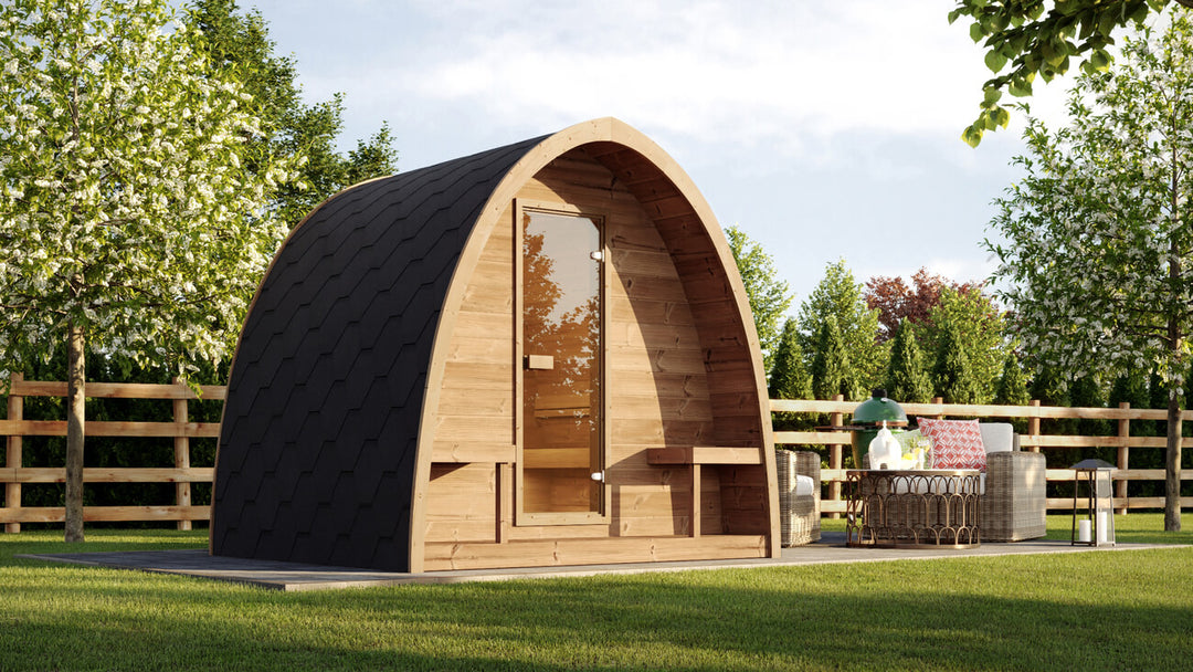 InMedias Sauna Pod 220 Outdoor Sauna installed on a wooden deck in a landscaped garden with trees and outdoor seating in the background.