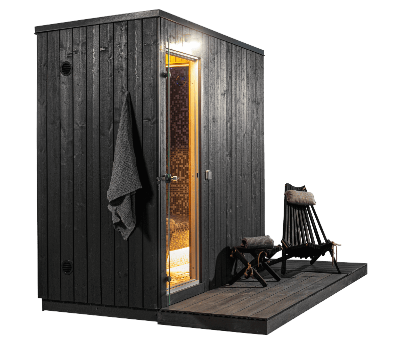KUUT 2-person steam sauna with a black wooden exterior, mosaic-tiled interior visible through open glass door, and two black lounge chairs on the wooden deck, on a transparent background.