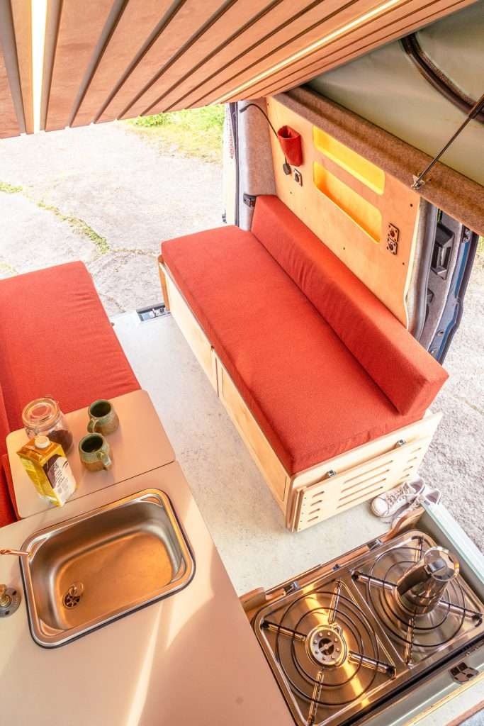 Top interior view of the Campervan Helm Kitchen Unit showing the sink, gas stove, and seating arrangement inside the campervan.