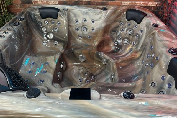 Interior of Luso Spas The Platinum 3 Hot Tub in dark marble acrylic with blue lighting, in an indoor showroom with brick wall background.